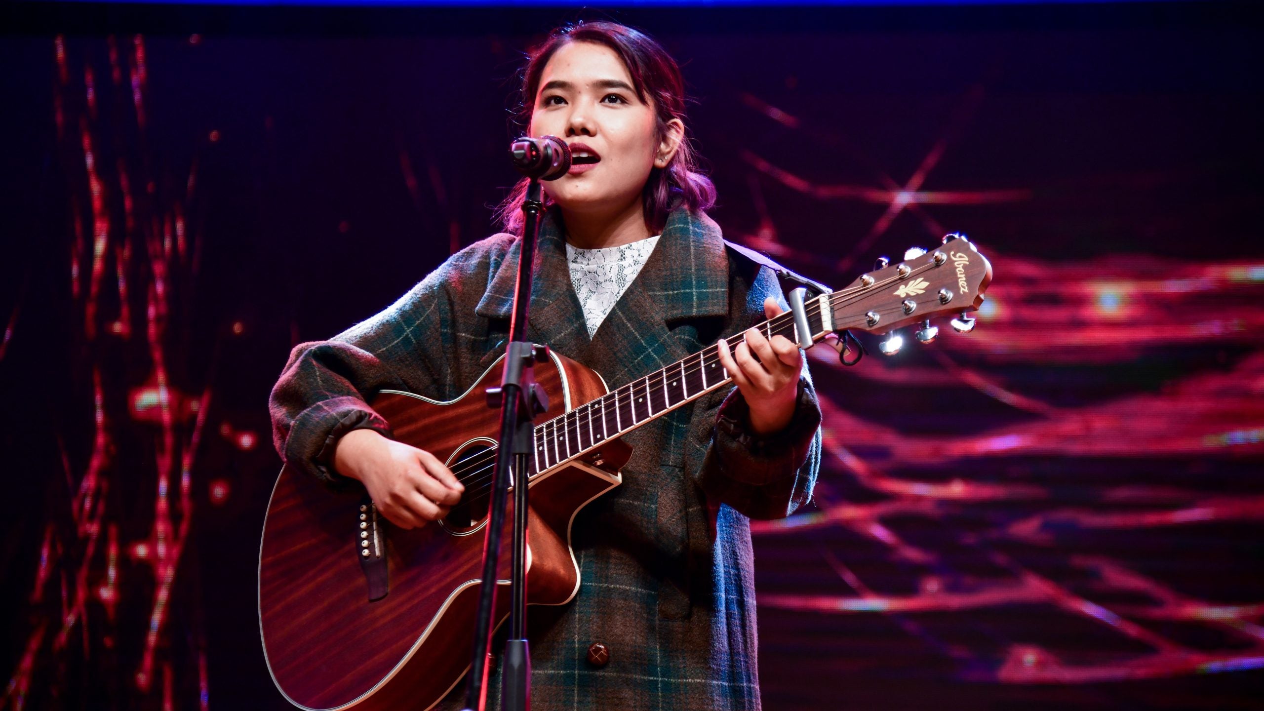 Carolina Norbu playing the guitar and singing on stage