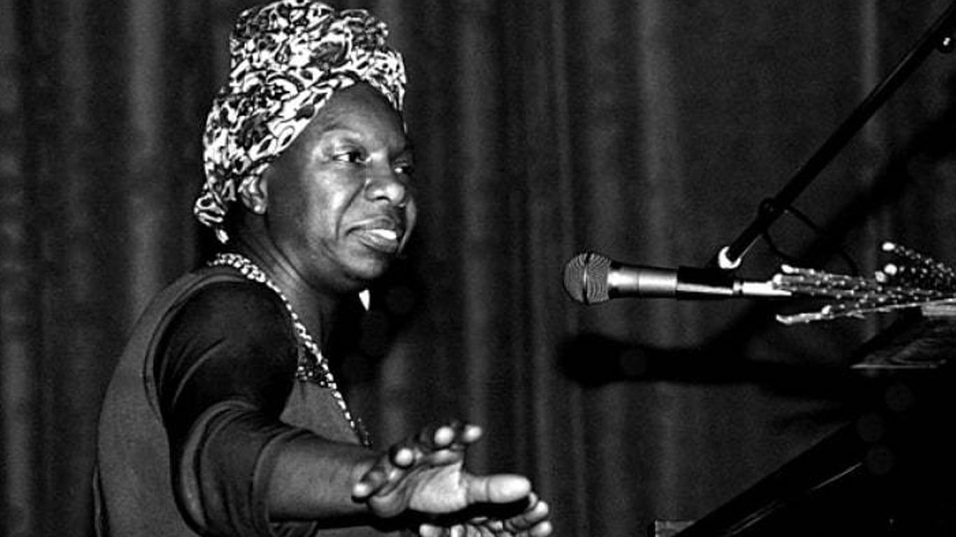 Nina Simone singing into microphone on stage