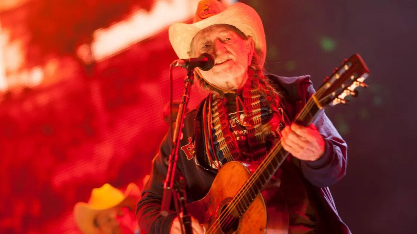 Willie Nelson performing live on stage playing the guitar and singing